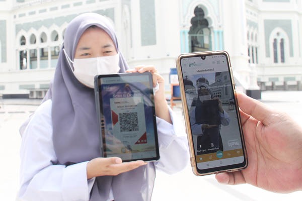 INFAQ DIGITAL BSI DI MASJID: Jamaah Masjid Raya Al Mashun Medan mempraktikkan cara scan QRIS BSI untuk berinfaq, Senin (21/11). BSI tidak mengambil keuntungan sepeser pun dari transaksi digital tersebut dan BSI berharap, dana sedekah masjid bisa terkordinasi lebih baik. Waspada/Surya Efendi