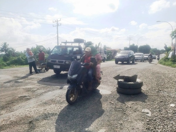 Warga sekitar yang memperbaiki jembatan dan memberi tahu kondisi rusak agar pengguna jalan berhati-hati.(Waspada/Edward Limbong).