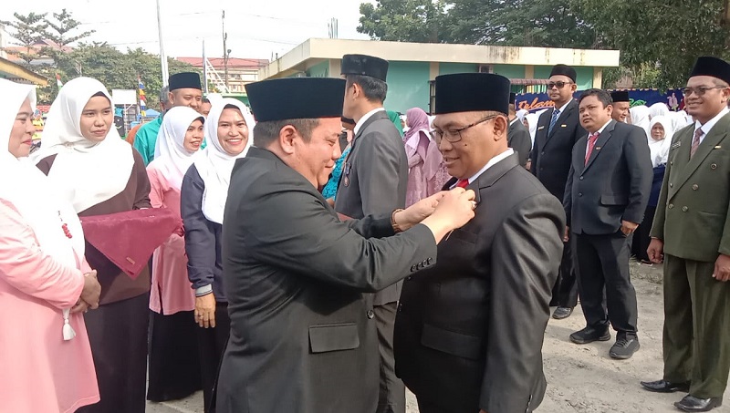 PLT.Kepala Kantor Kementerian Agama Deliserdang H.Fachrizal, SHI, MSi, menyematkan Satyalancana Karya Satya 10 tahun kepada Kepala KUA Batangkuis H.Muhammad Ruslan, MA, pada peringatan Hari Amal Bhakti ke 78 Tahun 2024 di halaman Kantor Kemenag Deliserdang, Rabu (3/1). (Waspada/Khairul K Siregar/B)