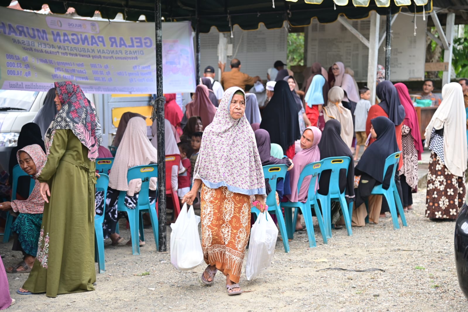 Salah satu warga membawa sembako yang dibeli di pasar murah yang digelar oleh Pemerintah Aceh Besar melalui Dinas Pangan bekerjasama dengan Perum Bulog Aceh serta Badan Pangan Nasional menggelar Gerakan Pangan Murah (GPM), di alaman Masjid Jami' Al Mukarramah, Indrapuri, Aceh Besar, Selasa (27/2). (Waspada/Ist)