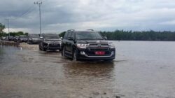 Mobil Dinas Pj Gubernur Bustami Hamzah bersama rombongan saat melintasi air pasang laut, di badan jalan Desa Kilangan menuju Desa Kayu Menang, Minggu (28/4) kemarin. WASPADA/Ariefh