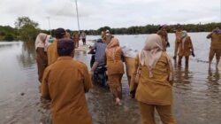 Masyarakat bersama para PNS dan pegawai honor di Kecamatan Singkil dan Kuala Baru, mendorong kendaraan yang melintas, saat menggelar aksi di jalan yang terendam banjir, Senin (20/5/2024). WASPADA/Ariefh