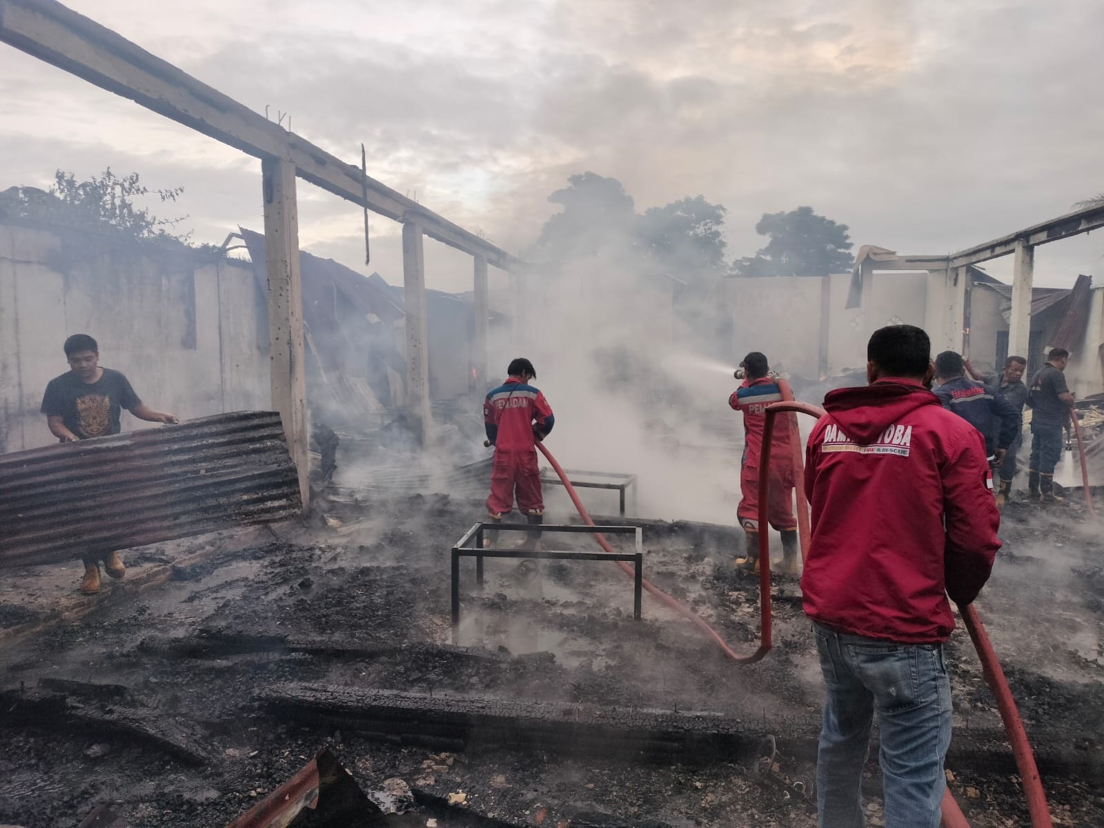 Petugas Damkar Pemkab Toba berupaya memadamkan api yang melahap Cafe Happy di Kecamatan Laguboti, Rabu (22/5). Waspada/Ist