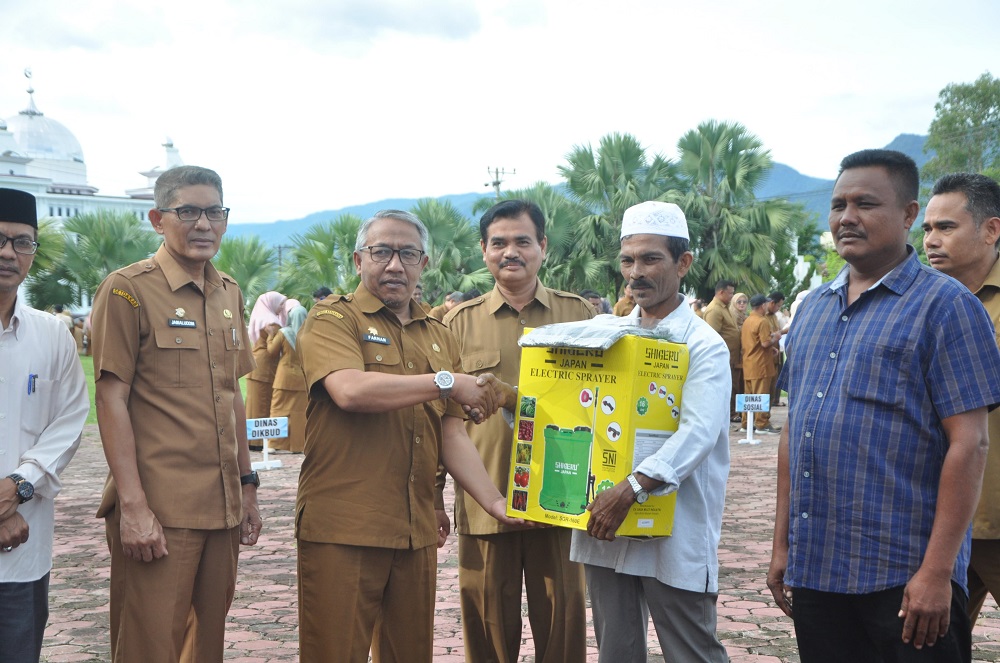 Asisten I Sekdakab Aceh Besar Farhan AP menyerahkan hand sprayer kepada para petani pada apel gabungan memperingati Hari Krida Pertanian tahun 2024, di halaman Kantor Bupati Aceh Besar, di Kota Jantho, Senin (24/6). (Waspada/Ist)