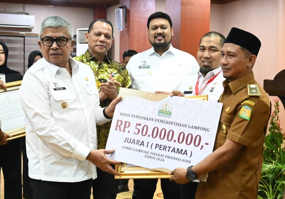 Keuchik Bueng Sidom, drh Muhammad Yanis didampingi Penjabat (Pj) Bupati Aceh Besar, Muhammad Iswanto, saat menerima hadiah Juara 1, Gampong (desa) Terbaik se-Aceh tahun 2024, yang diserahkan Pj. Gubernur Aceh, Bustami, Jumat (5/7). (Waspada/Ist)