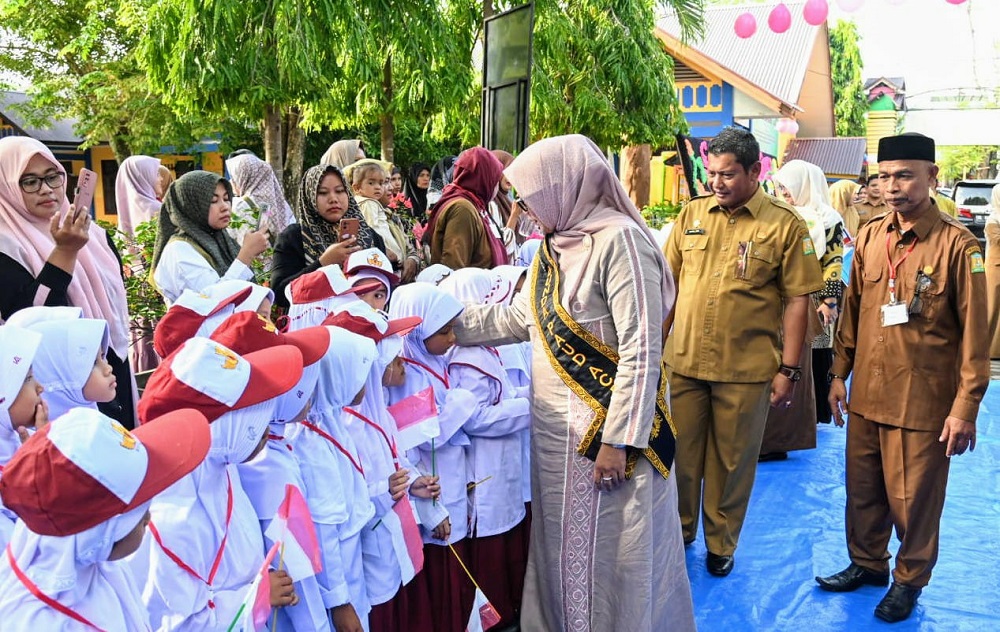 Pj Bunda PAUD Aceh Mellani Subarni bersalaman dengan murid baru saat berkunjung di SDN 1 Lampeuneurut, Kecamatan Darul Imarah, Aceh Besar, Senin (15/7). (Waspada/Ist)