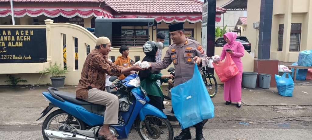 Kapolsek Kuta Alam, AKP Suriya, turun langsung ke jalan untuk membag-bagikan takjil kepada pengguna jalan yang melintas di depan Mapolsek Kuta Alam. (Waspada/Zafrullah)