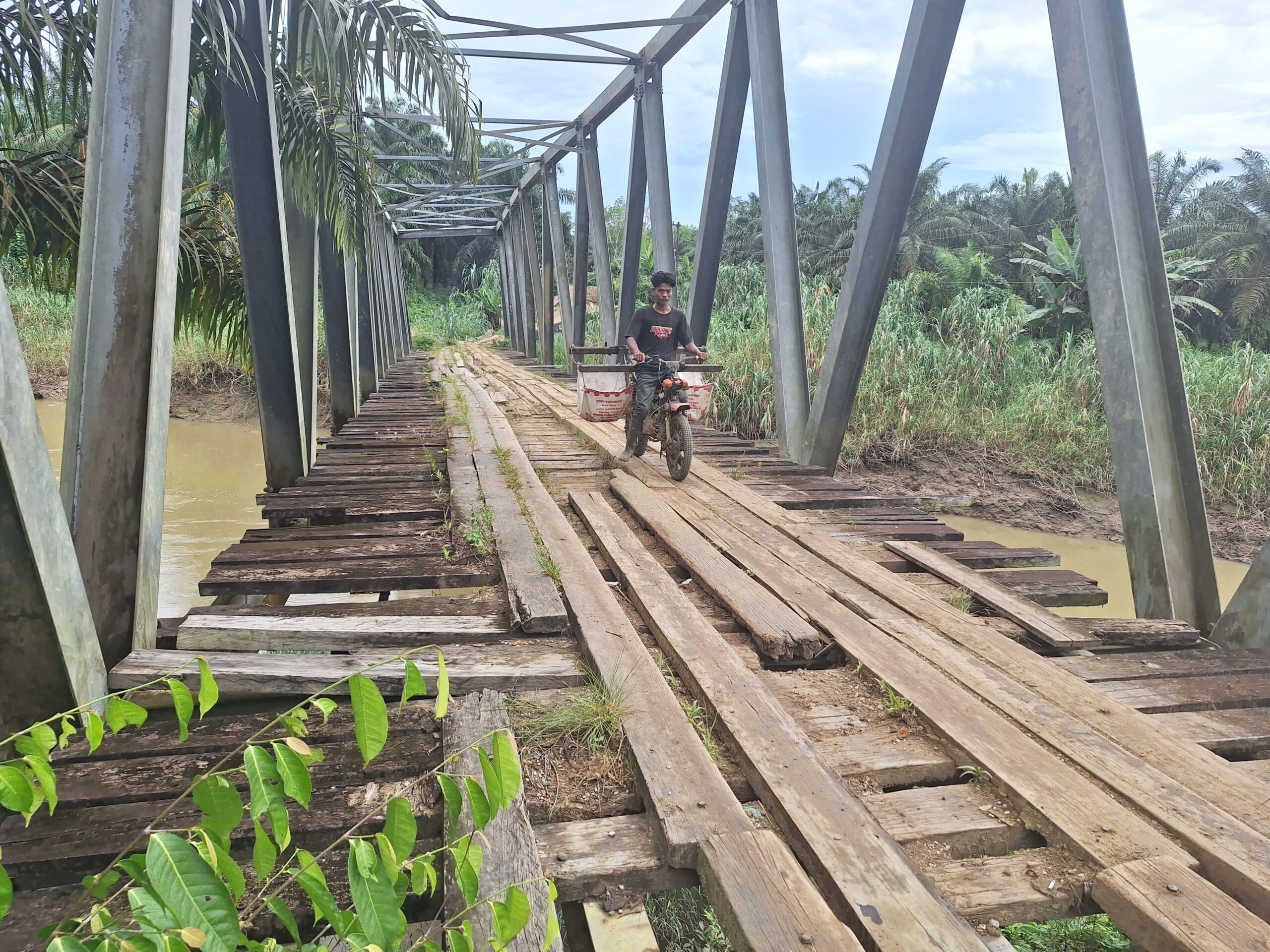 Warga melintasi jembatan yang nyaris ambruk di Rawa Pakis, untuk melansir logistik dari Peunaron Baru ke Sri Mulya, Kec. Peunaron, Kab. Aceh Timur, Rabu (12/3). Waspada/Muhammad Ishak