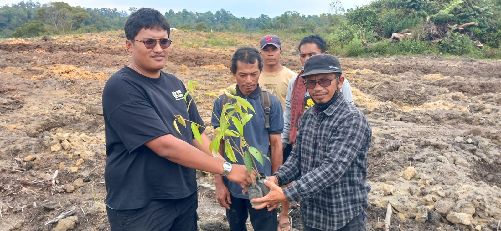 MASYARAKAT Desa Sitapongan, Andi Lumban Gaol menerima bibit pohon durian dari pihak pengusaha untuk ditanam di lahan bukaan pertanian. Waspada/Andi Siregar