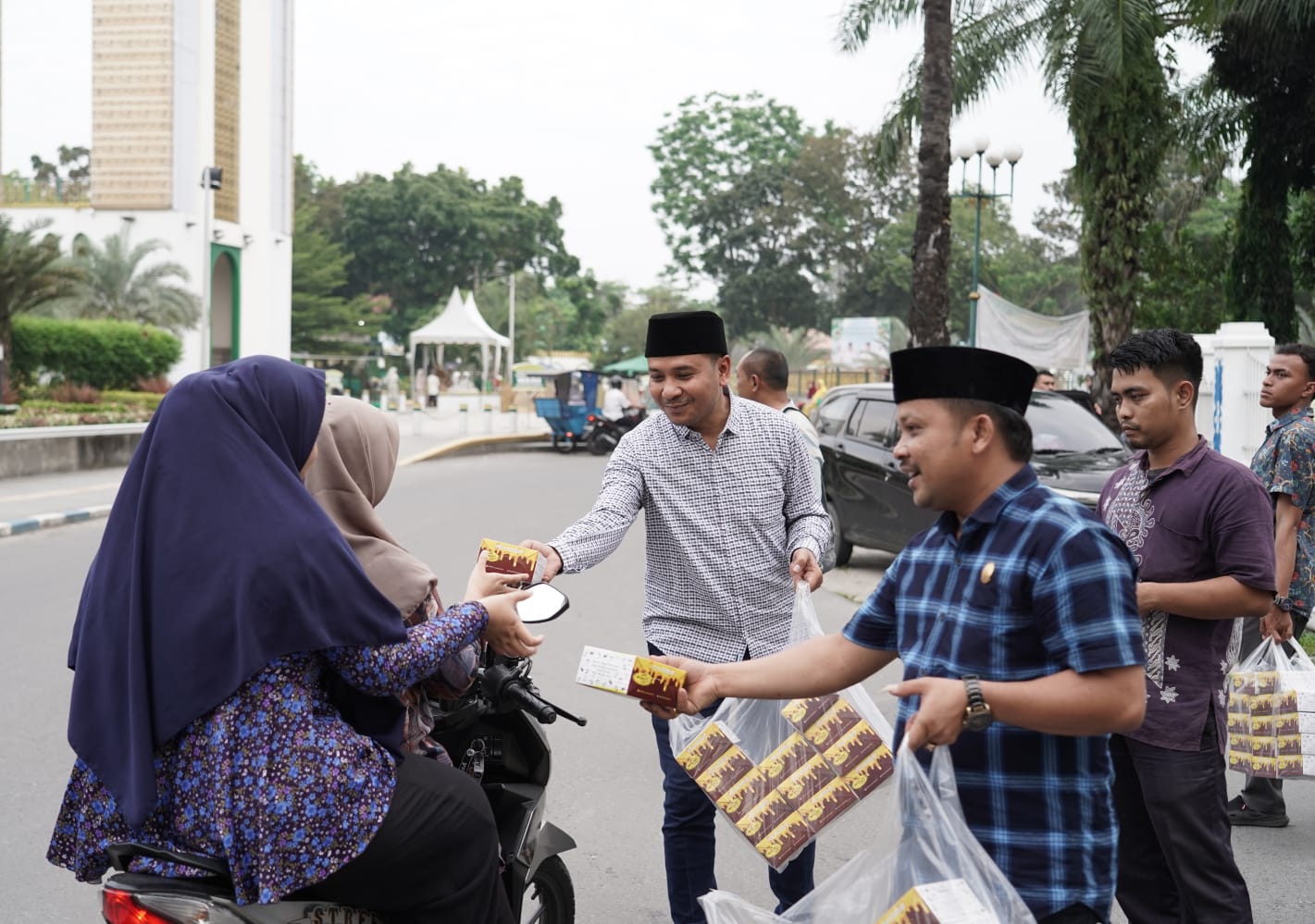 Ketua Komisi II DPRD Deliserdang, Muhammad Ilham Pulungan dan Anggota Komisi II DPRD Deliserdang Sehat Harianto Sembiring membagikan takjil kepada pengendara sepeda motor. (Waspada/Edward Limbong).